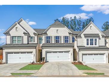 Charming townhome with white brick exterior, a two-car garage, and well manicured lawn at 4090 Cavalier Way, Duluth, GA 30097