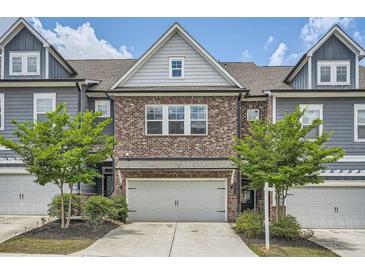 Charming townhome featuring a brick facade, two-car garage, and beautifully landscaped front yard at 2543 Oakbourne Ln # 14, Smyrna, GA 30080