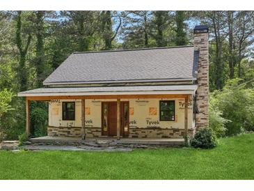Charming home featuring a stone chimney, covered porch, and lush green lawn at 2003 Greeson Rd, Dacula, GA 30019
