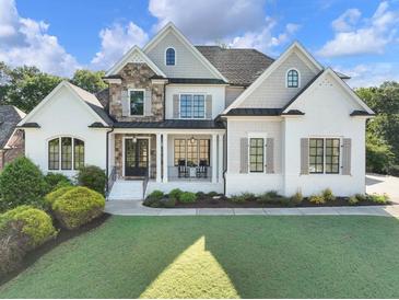 Beautiful two-story home with a manicured lawn, brick and stone accents, and black-trimmed windows at 1963 Skybrooke Ln, Hoschton, GA 30548