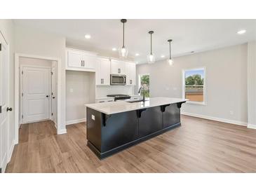 Modern kitchen features a large island with quartz countertops, white cabinetry and stainless steel microwave at 4523 Moray Dr, Mableton, GA 30126