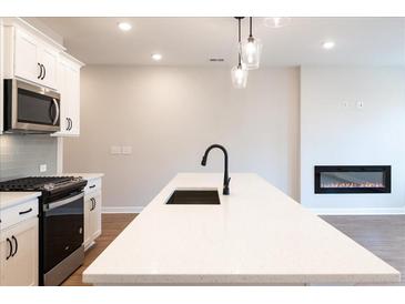 Modern kitchen with stainless steel appliances, white cabinets, island with seating, and a cozy fireplace at 4523 Moray Dr, Mableton, GA 30126