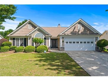 Charming single-story home with well-manicured lawn and lush landscaping under a clear blue sky at 3134 Milloak Ct, Buford, GA 30519