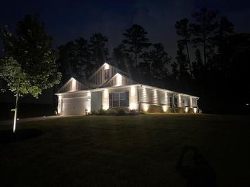Charming single-story home featuring stylish exterior lighting and well-manicured lawn at nighttime at 426 Samara Ct, Fairburn, GA 30213