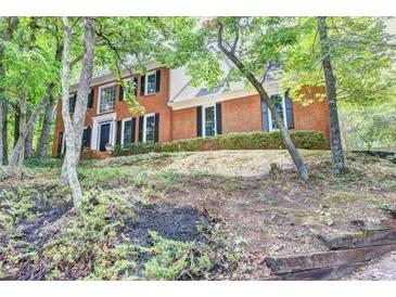 Traditional two-story brick home surrounded by mature trees and lush landscaping at 1825 Crescent Rdg, Cumming, GA 30041