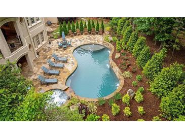 An inviting kidney-shaped pool and hot tub are surrounded by lush landscaping and patio furniture at 8109 Lawnview, Alpharetta, GA 30022