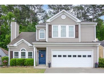 Charming two-story home featuring a blue front door, two-car garage, well-manicured lawn and traditional architectural details at 3381 Grovewood Ln, Duluth, GA 30096