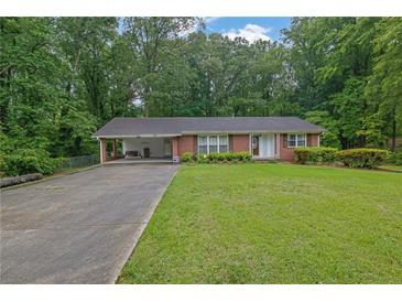 Charming brick home featuring a well-manicured lawn and attached carport at 1125 Lanier Sw Dr, Marietta, GA 30060
