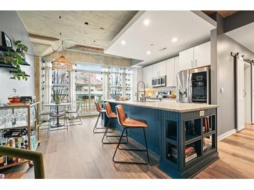 A kitchen with blue cabinets and a large island with seating for three, accented by a large window and modern appliances at 890 Memorial Se Dr # 102, Atlanta, GA 30316