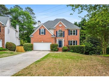 Charming two-story brick home with landscaped lawn, attached garage, and inviting dark blue front door at 7035 Hampton Bluff Way, Roswell, GA 30075