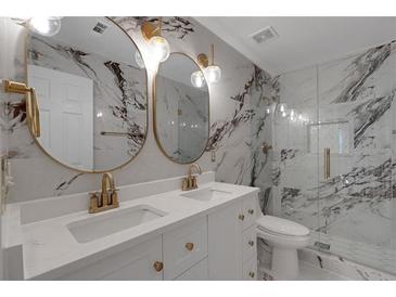 Modern bathroom featuring marble walls, double vanity, gold fixtures, and a glass-enclosed shower at 1095 Lyndhurst Way, Roswell, GA 30075