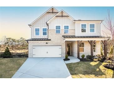 Charming two-story home with a white brick facade, a covered porch with stone pillars, and a two-car garage at 5121 Hillside Haven Drive, Powder Springs, GA 30127