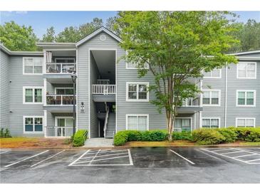Condominium exterior showing gray siding, white trim, balconies, mature trees, and wet parking lot at 6204 Santa Fe Pkwy, Atlanta, GA 30350