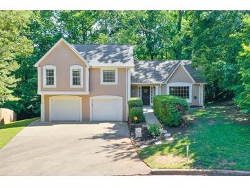 Charming two-story home features a two-car garage and a welcoming front entrance with lush landscaping and mature trees at 804 Rose Creek Walk, Woodstock, GA 30189