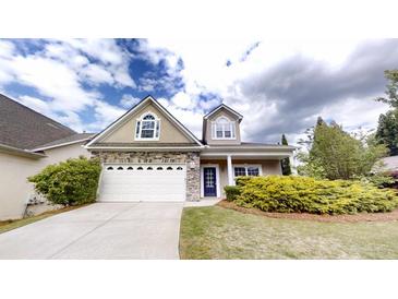 Charming home featuring a stone facade, white garage door, well-manicured lawn, and inviting blue front door at 900 Ellesmere Pt, Mcdonough, GA 30253