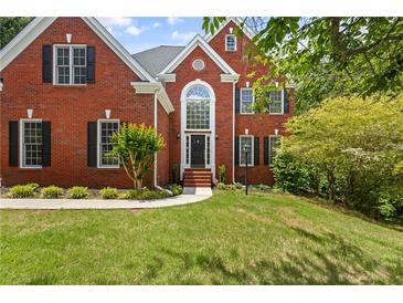 Charming two-story red brick home with lush green lawn and mature trees at 3014 Volland Grove Trail, Lawrenceville, GA 30043