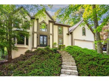 Charming two-story home with stone stairs and lush landscaping on a sunny day at 11950 Wildwood Springs Dr, Roswell, GA 30075