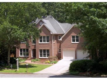 Charming two-story red brick home with a well-manicured lawn, beautiful trees and a driveway leading to a two-car garage at 1243 Williamswood Pointe, Decatur, GA 30033