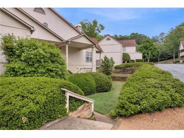 View of condo with beige exterior, manicured bushes, and staircase leading to front door at 203 Bridge Se Ln, Smyrna, GA 30082