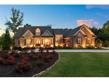 Beautiful stone and brick home featuring a lush, landscaped front yard and well-lit exterior at 341 Carl Sanders Dr, Acworth, GA 30101