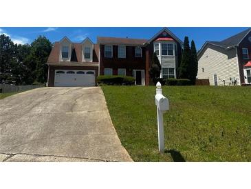 Charming two-story brick home with attached two car garage, manicured lawn, and long driveway at 8529 Glendevon Ct, Riverdale, GA 30274