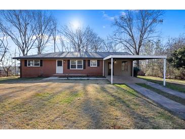 Charming brick home with a carport, lush lawn and classic design creating a welcoming curb appeal at 7427 Hollis Rd, Douglasville, GA 30135