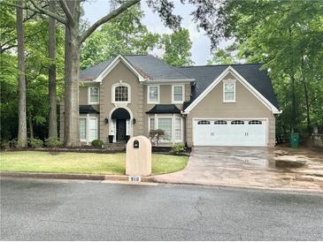Charming two-story home with attached two-car garage and well-manicured front yard at 910 Kings Arms Way, Alpharetta, GA 30022
