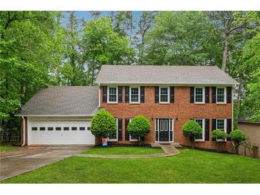 Charming two-story brick home featuring a well-manicured lawn, mature trees, and a two-car garage at 745 Greenvine Pl, Roswell, GA 30076