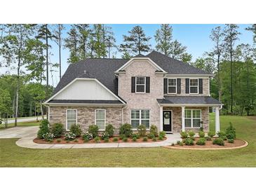 Beautiful two-story home featuring a combination of stone and brick, a dark roof, and a neatly landscaped front yard at 130 W Pier Way, Fayetteville, GA 30214