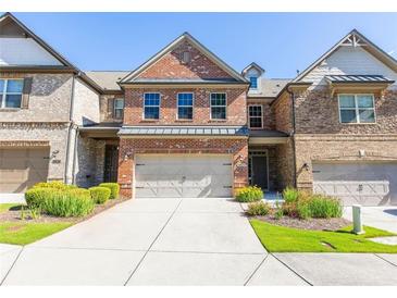Beautiful brick townhome featuring a two-car garage and well-manicured landscaping at 9872 Cameron Parc Cir, Johns Creek, GA 30022
