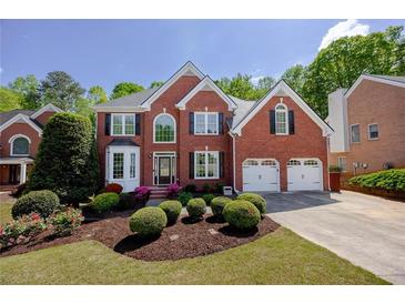 Beautiful brick home featuring a manicured front yard with flowering shrubs and a two-car garage at 1105 Anemone Nw Way, Acworth, GA 30102
