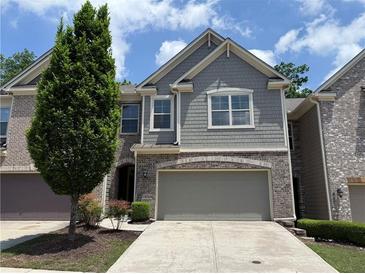 Charming two-story townhome with a neutral color scheme, two-car garage, and a well-maintained front yard at 1632 Lenox Overlook Ne Rd, Brookhaven, GA 30329