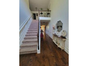 Bright foyer featuring hardwood floors, staircase, and decorative console table adding elegance to the home's entrance at 65 Waters Edge Ln, Covington, GA 30014