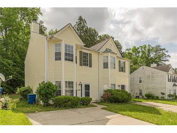 Charming two-story home featuring yellow siding, a landscaped yard, and a cozy covered entry at 5680 Hampton Ct, Atlanta, GA 30349