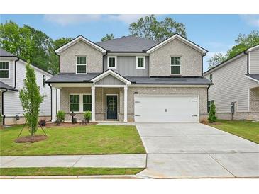 Charming home featuring a gray brick facade, a two-car garage, and a neatly manicured front lawn at 3970 Brushy St, Powder Springs, GA 30127