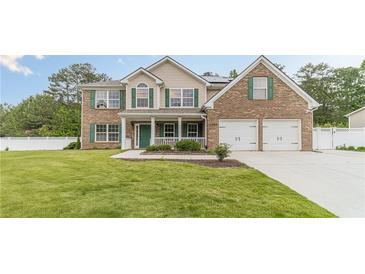 Inviting two-story brick home with a manicured lawn, covered front porch, and a two-car garage at 1349 Mckinsey Rdg, Loganville, GA 30052