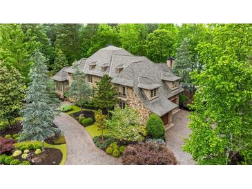 Stunning stone home with lush landscaping, a brick driveway, and a three-car garage surrounded by mature trees at 939 Middle Fork Trl, Suwanee, GA 30024