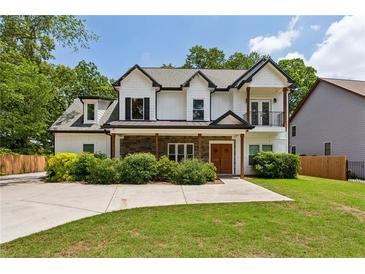 Charming two-story home featuring a stone facade, covered porch, and a manicured lawn at 2721 Old Concord Se Rd, Smyrna, GA 30082
