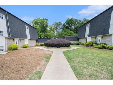 Attractive townhouse complex with manicured landscaping and a walkway on a sunny day at 5245 Chemin De Vie, Atlanta, GA 30342