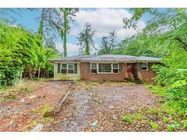 Overgrown front yard and exterior of brick house, ready to be revived with landscaping and repair at 2322 Paces Ferry Se Rd, Smyrna, GA 30080