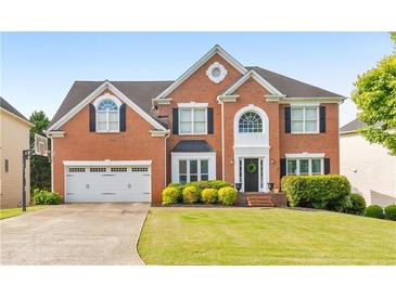 Traditional two-story brick home featuring a well-maintained lawn, two-car garage, and beautiful landscaping at 1730 Millhouse Run, Marietta, GA 30066