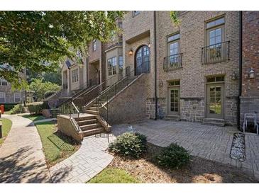 Elegant brick townhome featuring stone accents, arched entry door, and wrought iron detailing on a beautifully landscaped walkway at 538 Micayne Cir # 3, Smyrna, GA 30082