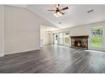 Spacious living room with wood flooring, stone fireplace, ceiling fan, and bright windows at 520 Cranberry Pl, Roswell, GA 30076