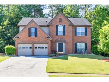 A two-story brick home with a well-manicured lawn, mature trees, and a two-car garage at 1500 Highland Farm Dr, Suwanee, GA 30024