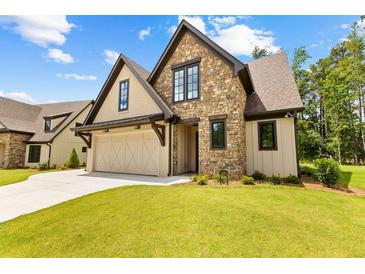 Attractive home featuring stone and stucco accents, a multi-car garage, and a green lawn at 208 Regester Way, Peachtree City, GA 30269