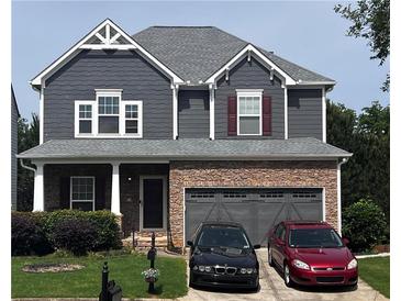 Charming two-story home with stone accents, a gray exterior, a well-maintained lawn, and an attached two-car garage at 3864 Lake Sanctuary Way, Atlanta, GA 30349