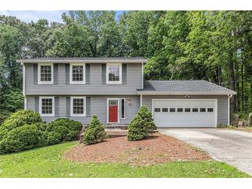 Charming two-story home with gray siding, red door, attached garage and a well-manicured front yard at 1023 Chartley Sw Dr, Lilburn, GA 30047