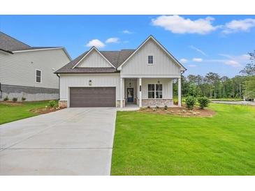 Charming one-story home featuring a well-manicured lawn, covered porch, and attached garage at 1101 Cooks Farm Way, Woodstock, GA 30189