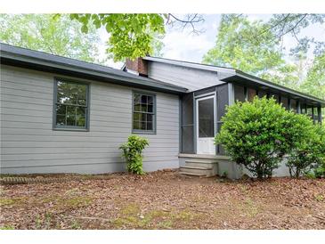 Charming home featuring a screened porch and gray siding, nestled among lush greenery for privacy at 147 Harris Loop, Dallas, GA 30157
