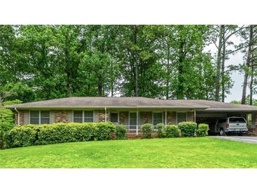 Charming brick home with a well-manicured lawn, mature trees, and a convenient carport at 3549 Dogwood Dr, Powder Springs, GA 30127